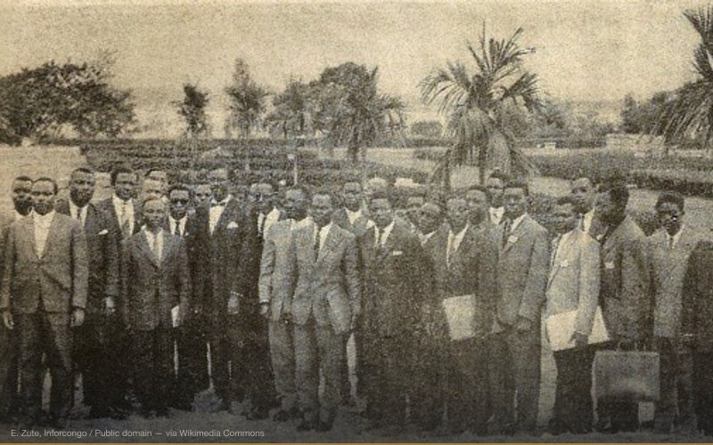Patrice Lumumba (left center) poses with his government outside the Palais de la Nation immediately following his swearing-in ceremony. Joseph-Désiré Mobutu is fifth from the right, in sunglasses. Pierre Mulele is third from the right. Marcel Bisukiro is fourth from the left. Thomas Kanza is eighth from the right, in the back, partially obscured — related to Patrice Lumumba — CIA/Belgian Assassination