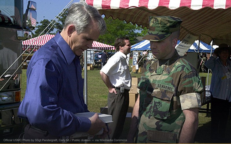 Oliver North signing one of his books at the Sea Services Korean War Commemoration Event at Camp Lejeune, North Carolina on April 11, 2002. Oliver North signs a copy of his book for SSgt Frank A. Manfre of Range Control, Bravo Company, Marine Corps Base, at the recent Korean War Commemorative event held at Camp Lejeune, North Carolina. Official USMC Photo by SSgt Pendergraft, Carly M. — related to Rex 84 — Martial Law & Civilian Detention Plan