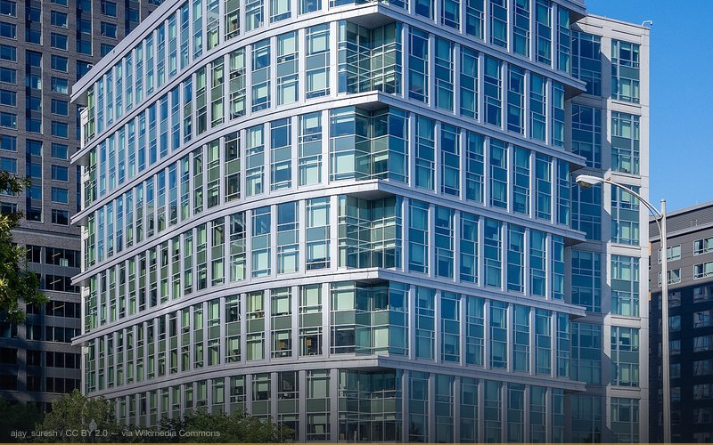 The headquarters of the Defense Advanced Research Projects Agency in Ballston, Virginia. The Mercedes-Benz luxury cars in the foreground do not belong to DARPA; they are parked on the used car lot of an adjacent Mercedes-Benz car dealership. — related to Total Information Awareness — DARPA Mass Surveillance Program